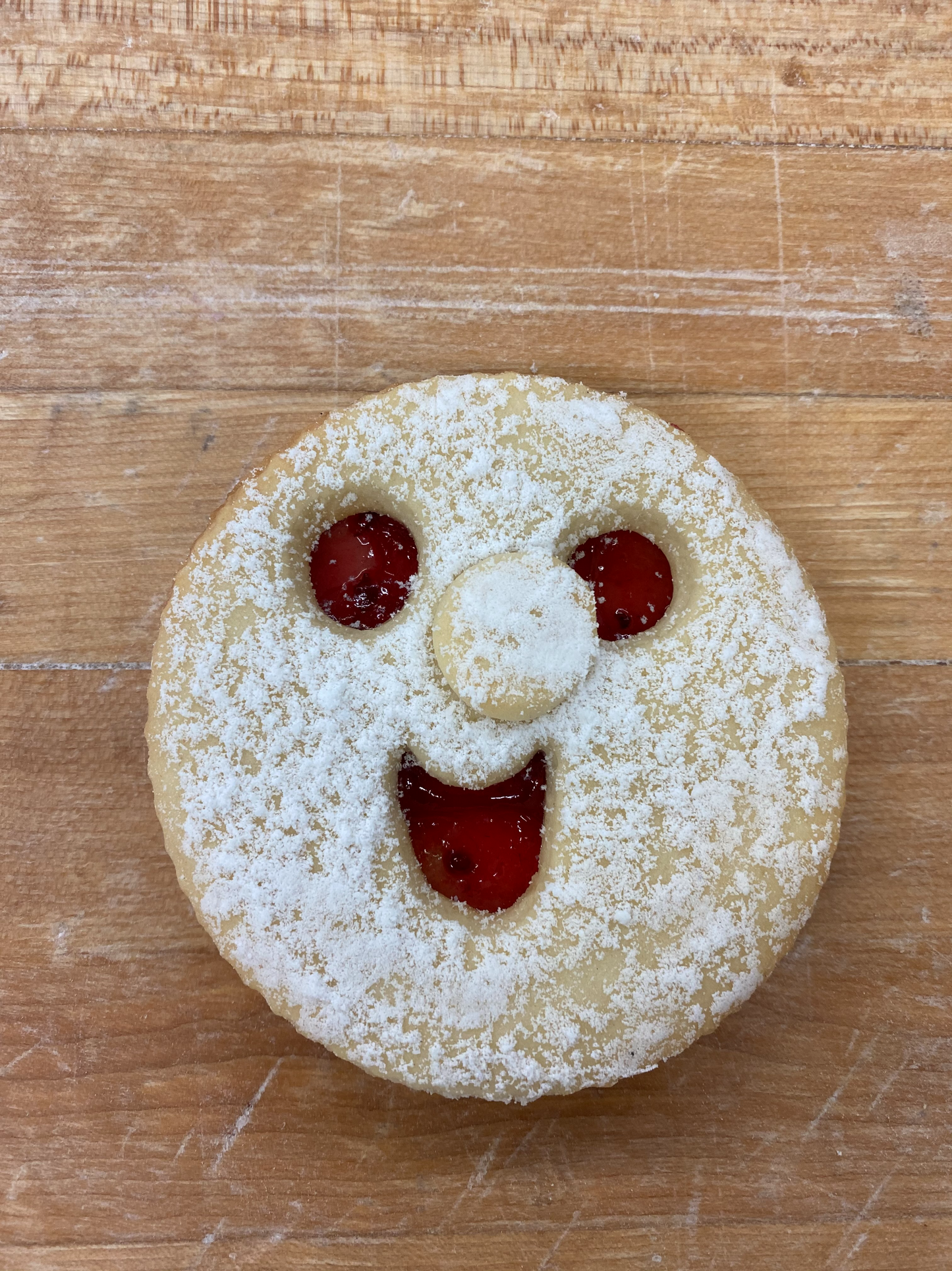 Two layers of sugar cookie with a raspberry filling and sprinkled with icing sugar